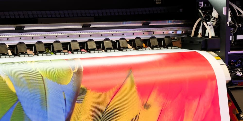 printer support Close-up of a wide-format digital printer producing a vibrant color banner for printer support.
